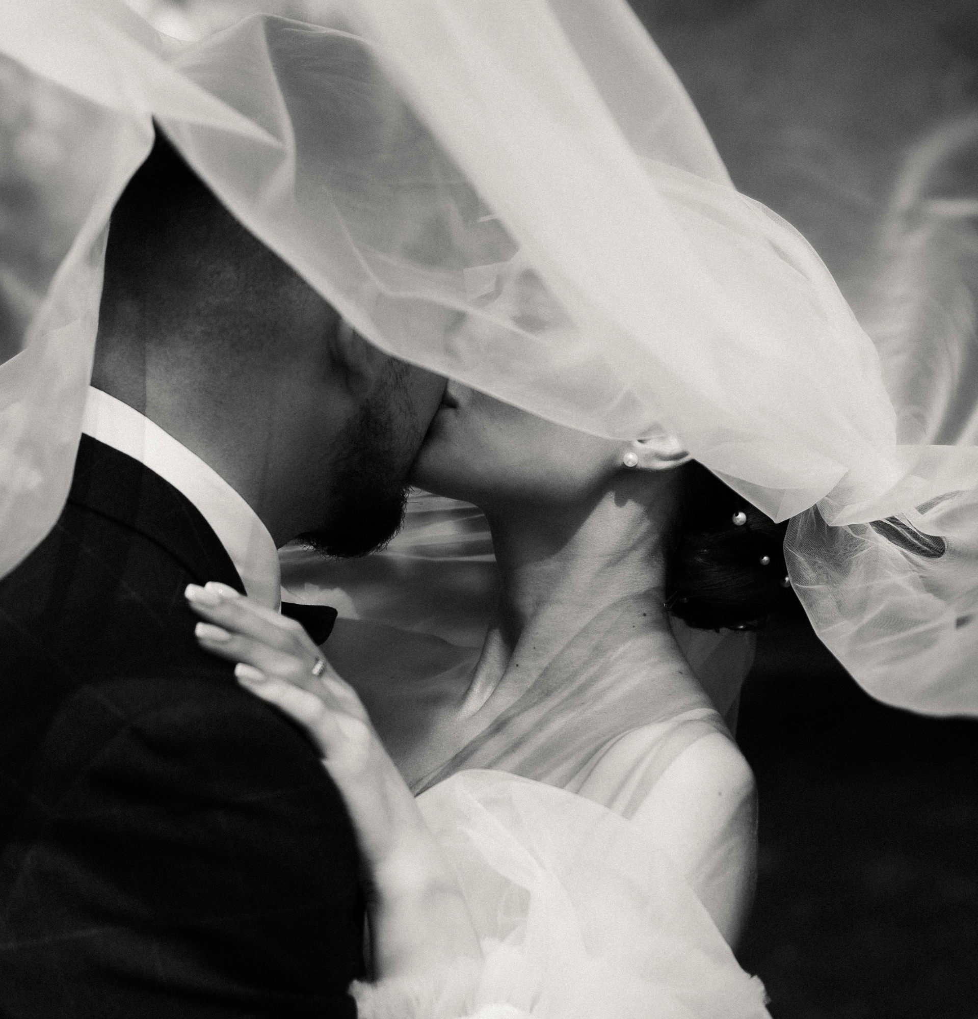 bride and groom kissing under bride's veil