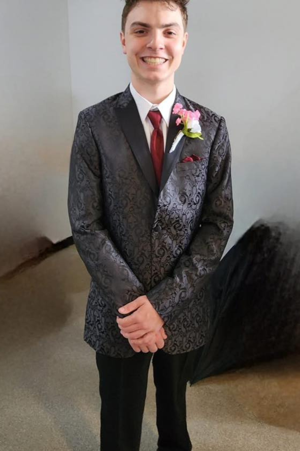 A box in a black tux with a red tie and pink flower.