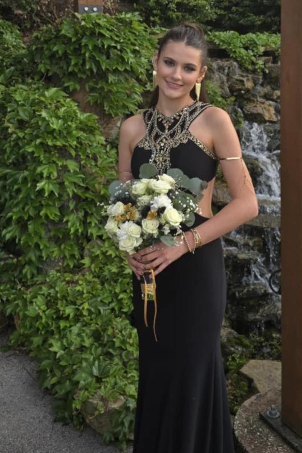 A girl wearing a black dress with a sparkly adornments.