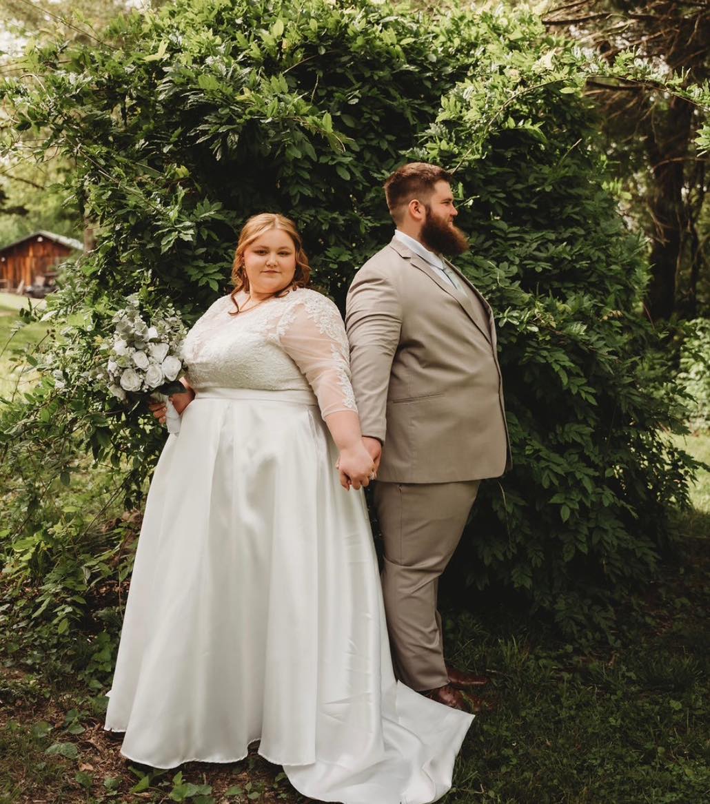 Bride wearing a customized Black Tie Affair dress standing back to back with groom.